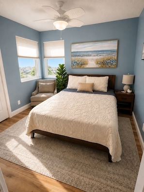 A bedroom with a bed, a nightstand, a lamp, a plant, and a painting on the wall.