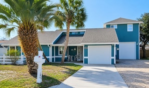 A two-story house with a garage, a covered porch, and a palm tree in the front yard. - Perfect Family Home | Private Pool • Walk to Beach (Panama City Beach)