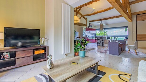 A modern living room with a TV, wooden furniture, a dining area, and a view of the outdoors. - Le Clos des Vignes - VERZE (VERZE)