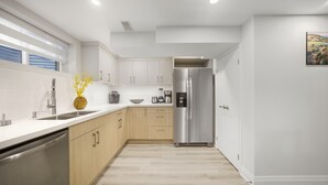 A modern kitchen with white cabinets, a stainless steel refrigerator, and a dishwasher. - Charming Streetsville 2BR Suite-Parking & Laundry (Mississauga)