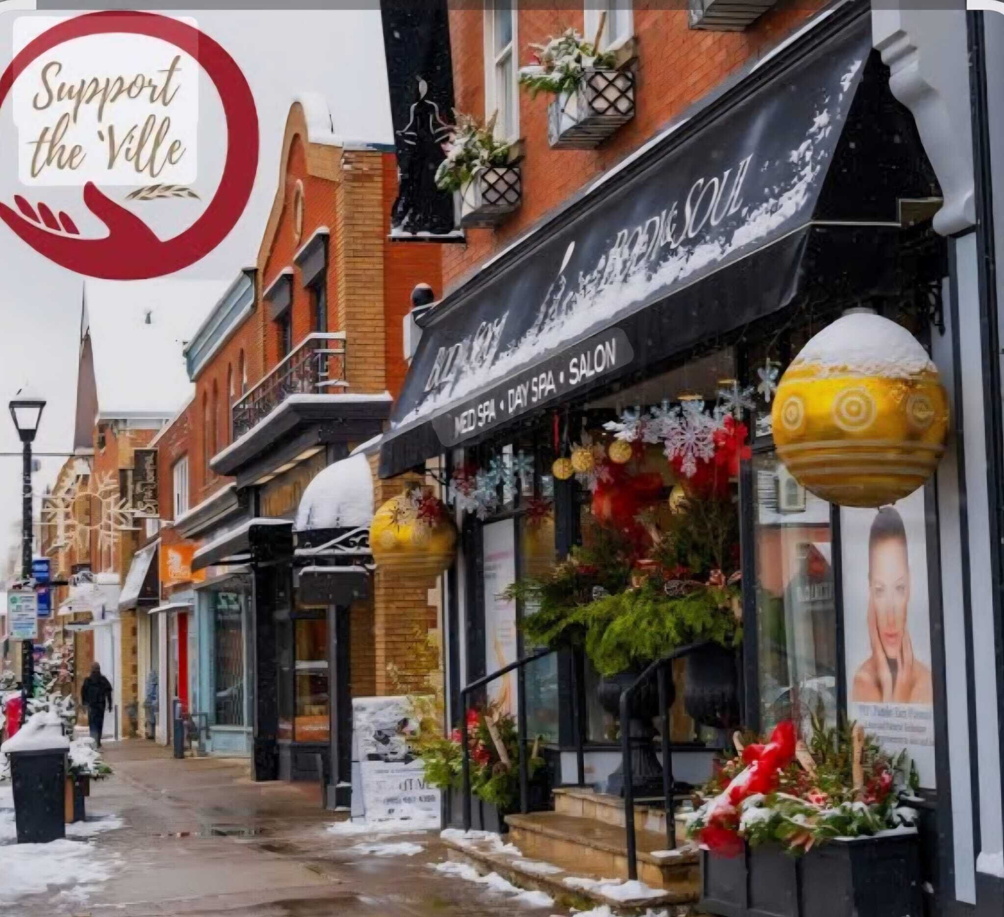 A street with a building featuring a black awning and a sign for a day spa and salon.
