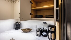 A compact kitchen with a toaster, blender, coffee maker, and a bowl on the counter. - Charming Streetsville 2BR Suite-Parking & Laundry (Mississauga)