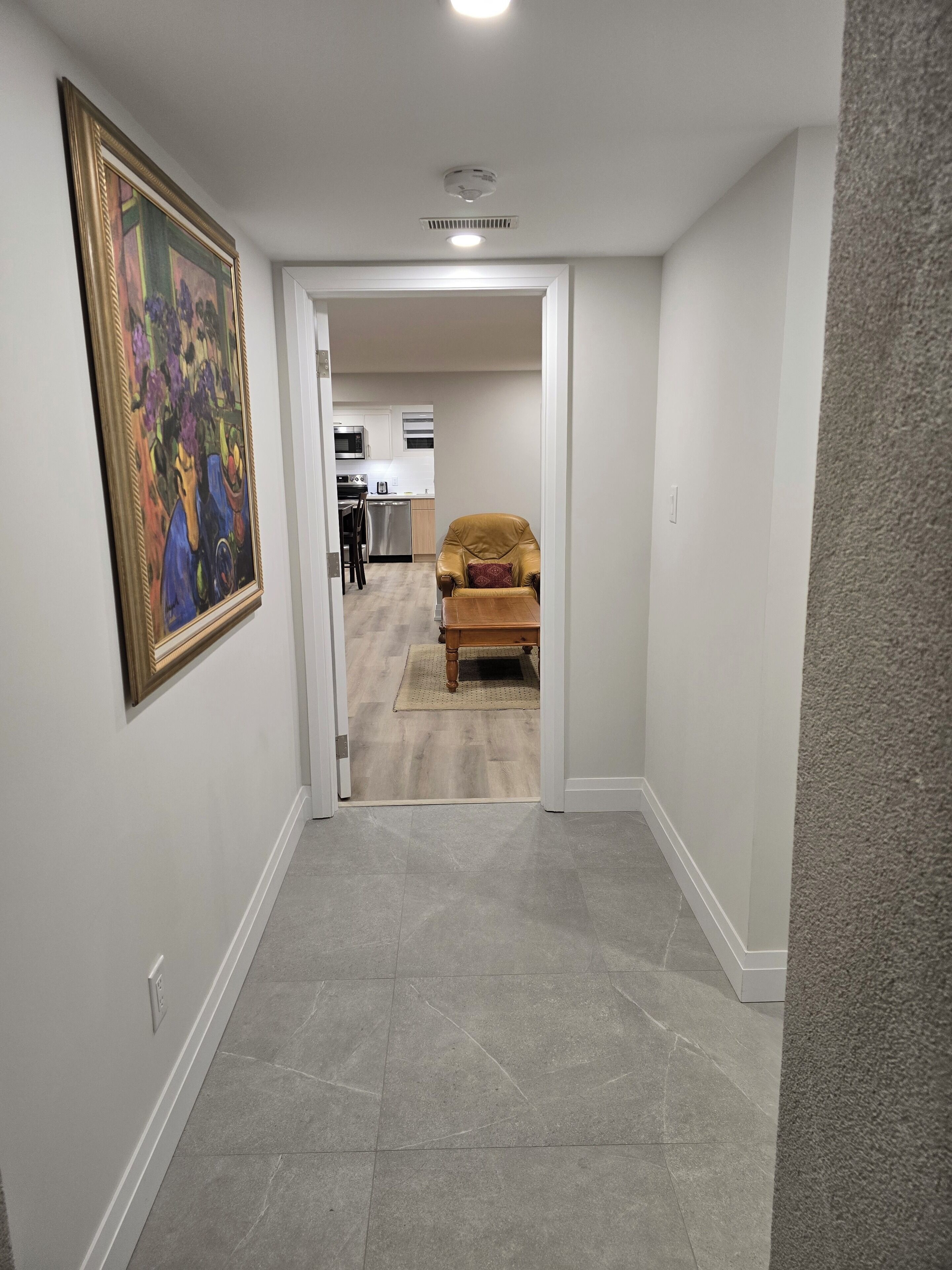 A hallway with a dining area, a kitchen, and a living room.