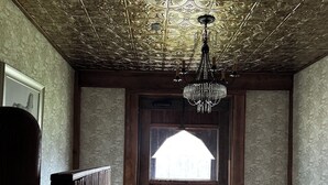 Una puerta de madera con un ventanal, un candelabro, papel tapiz con diseño y suelo con estampado de ladrillos.