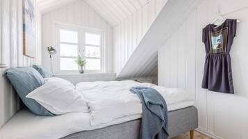 A bedroom with a loft bed, a window, a plant, and a hanging dress.