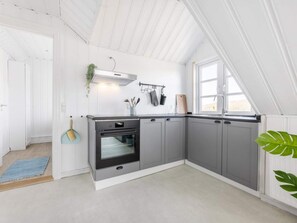 Eine moderne Küche mit grauen Schränken, einem Einbauofen und einem Fenster, das für natürliches Licht sorgt.