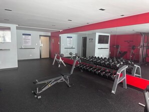 A gym with weightlifting equipment, a bench press, and a mirror wall. - Comfortable and Central Apartment in Santo Domingo. (Santo Domingo)