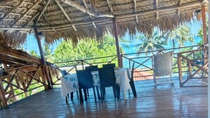 A covered outdoor area with wooden flooring, tables with white tablecloths, and chairs. - Exclusive villa for rent in Juan Dolio private second line beach 1 min. (Playa Juan Dolio)