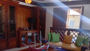 A room with a wooden coffee table, a sofa with cushions, a telephone, and a ceiling fan. - Exclusive villa for rent in Juan Dolio private second line beach 1 min. (Playa Juan Dolio)