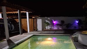 A rectangular swimming pool with clear water, surrounded by a wooden deck and a covered area with pillars. - Exclusive villa for rent in Juan Dolio private second line beach 1 min. (Playa Juan Dolio)