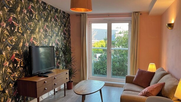 A living room with a television, sofa, and a small table.