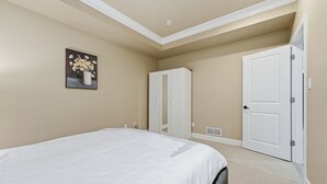 A bedroom with a bed, a white door, and a closet. - 3BR Suite near White Rock Beach • Pool & BBQ (Surrey)