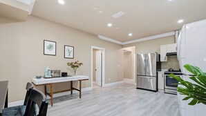 A modern kitchen with a refrigerator, oven, and dining area with a table and chairs. - 3BR Suite near White Rock Beach • Pool & BBQ (Surrey)