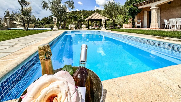 Una piscina con una botella de vino y una rosa en el borde.
