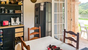 Una cocina con refrigerador, una mesa de comedor, sillas y vista al exterior.