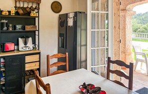 Eine Küche mit Kühlschrank, Esstisch, Stühlen und Blick ins Freie.