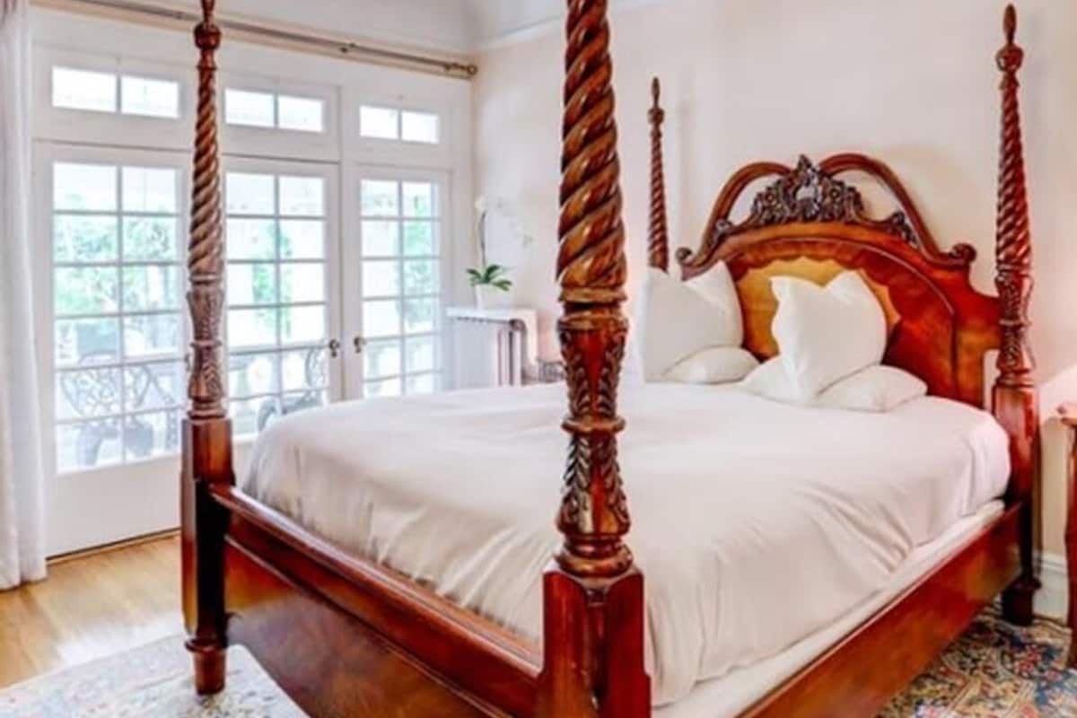 Un lit à baldaquin agrémenté d’un lustre, une grande fenêtre et un tapis à motifs.