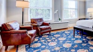 Una habitación con cama, silla, lámpara y radiador.