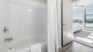 Un baño moderno con azulejos blancos tipo metro, una bañera y una ducha.