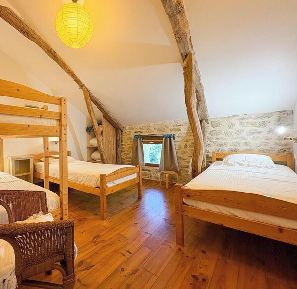 A rustic room with wooden bunk beds, a wicker chair, and a stone wall. - Rocamadour - TRESPOUX RASSIELS (TRESPOUX RASSIELS)