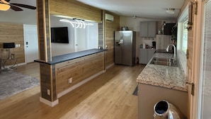 A modern kitchen with wooden cabinetry, a built-in island, stainless steel appliances, and a ceiling fan. - Lakefront 3BR/2BATH with Private Dock on 3/4 Acre in terrific Nocona with AC (Nocona)