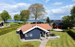 A coastal vacation home with a red roof, a covered porch, and a view of the sea. - Cozy home in Otterup with sauna (Otterup)