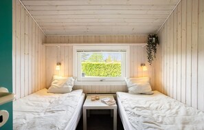 A cabin with two beds, a small table, and a window with a view of greenery. - Cozy home in Otterup with sauna (Otterup)