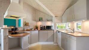 Una cocina moderna con armarios de madera, un microondas integrado y un ventanal que proporciona luz natural.