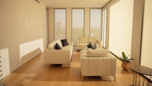 A modern living room with a sofa, armchair, and coffee table, large windows, and a plant. - Mr. W | Modern 2 bedroom apartment in Providencia (Zapopan)