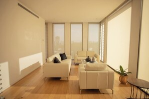 A modern living room with a sofa, armchair, and coffee table, large windows, and a plant. - Mr. W | Modern 2 bedroom apartment in Providencia (Zapopan)