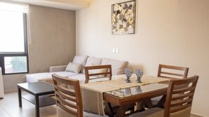 A dining area with a table, chairs, and a sofa in the background.