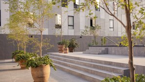 A modern building with a courtyard, steps leading to an upper level, and potted plants.