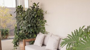 A modern living room with a sofa, a wooden coffee table, and a large potted plant.