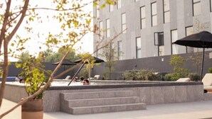 A modern building with a pool area, outdoor seating, and steps leading to a terrace.
