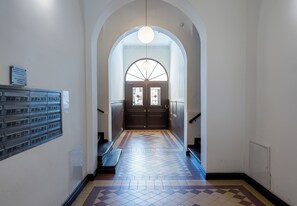 A hallway with a patterned floor, a large arched doorway, and a light fixture above. - Kopernika Old Town Apartment (Poznań)