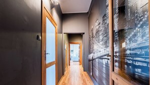 Een hal met houten vloer, een glazen deur en een muur met een stadsgezichtsmural.
