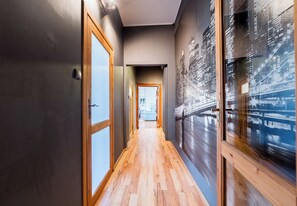 A hallway with wooden flooring, a glass door, and a wall with a cityscape mural. - Kopernika Old Town Apartment (Poznań)