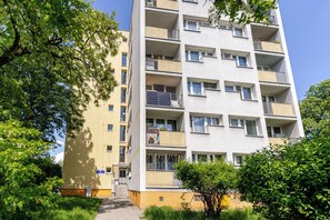 Ein mehrgeschossiges Wohngebäude mit Balkonen, einem sichtbaren Eingang und blauem Himmel.