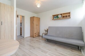 Ein modernes Wohnzimmer mit einem grauen Sofa, einem Holzschrank und einem kleinen Tisch.