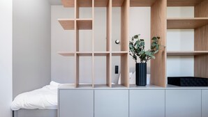 A modern bedroom with a bed, a grey wardrobe, and a wooden shelving unit.