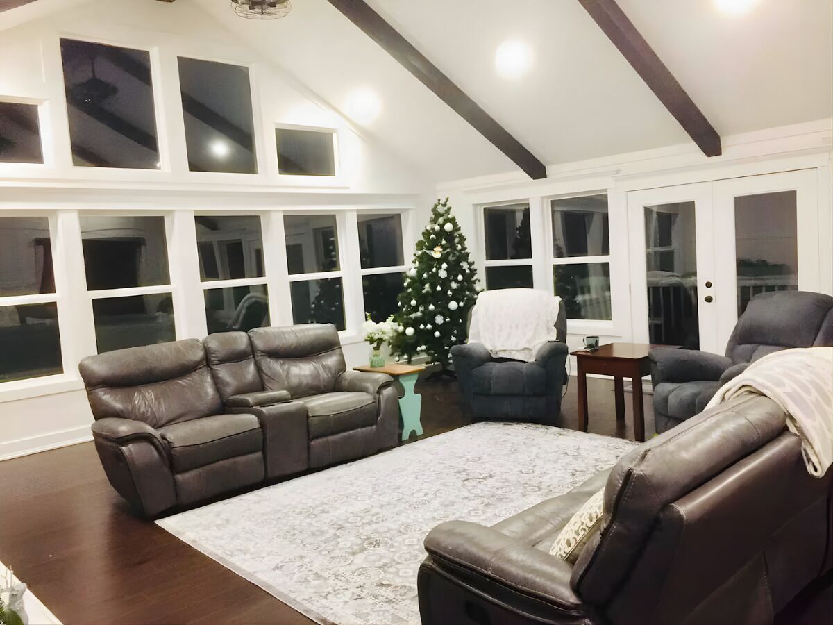Een woonkamer met een leren bank, een bijzettafeltje en een kerstboom.