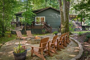 A wooden deck with Adirondack chairs, a stone fire pit, and a house with a deck and stairs. - Creekside Green - Firepit | Gazebo alongside creek | pond (Cherry Log)