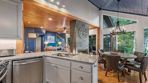 A modern kitchen with granite countertops, a built-in dishwasher, and a stone accent wall. - Blue Moon Rise - Pet Friendly | Mountain View | Hot Tub (Blue Ridge)