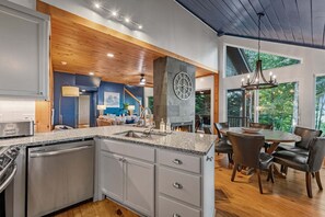 A modern kitchen with granite countertops, a built-in dishwasher, and a stone accent wall. - Blue Moon Rise - Pet Friendly | Mountain View | Hot Tub (Blue Ridge)