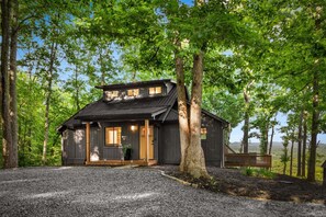 A cabin with a sloped roof, wooden exterior, and a porch with a bench. - Blue Moon Rise - Pet Friendly | Mountain View | Hot Tub (Blue Ridge)