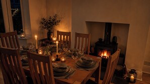Ein Esszimmer mit Holztisch, gedeckt für sechs Personen, umgeben von Stühlen, einer Blumenvase und einem Kamin.