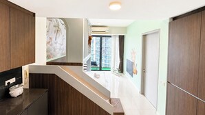 Una cocina moderna con estufa integrada, una escalera que lleva a un balcón y vistas de edificios altos.