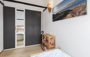 Ein Schlafzimmer mit einem Bett, einem Nachttisch aus Holz, einem Kleiderschrank und einem Bild mit Strandmotiv.