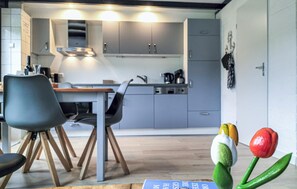 Eine moderne Küche mit grauen Schränken, einem Holzespeisetisch und Stühlen. Zwei Leuchten befinden sich über den Schränken.
