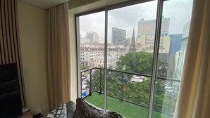 A room with a large window, a balcony with a metal railing, and a view of city buildings and greenery. - Cape Town Urban Elegance on Long Street | Unbeatable Table Mountain View’s (Cape Town)